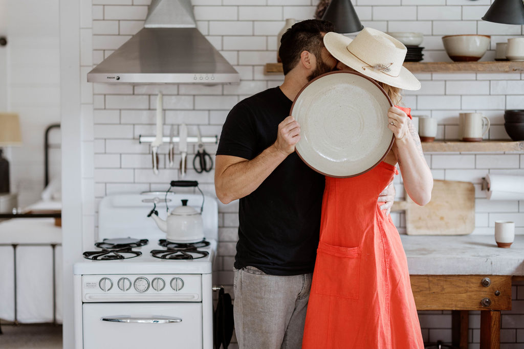Kali and Jeffrey holding a handmade ceramic platter in their kitchen