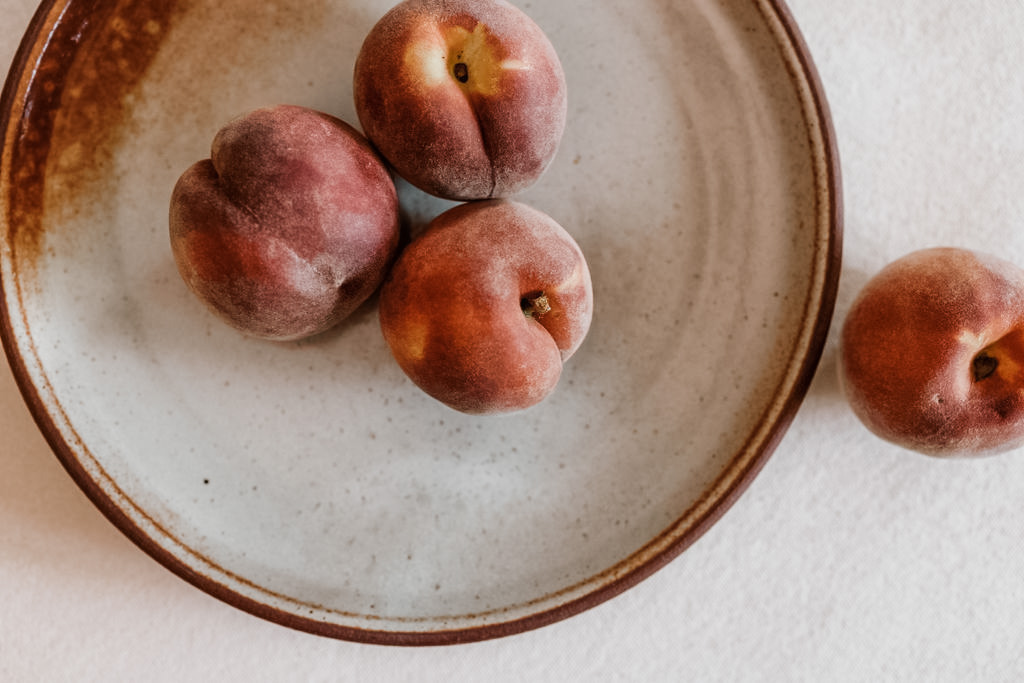 Fresh peaches arranged on a handmade ceramic platter